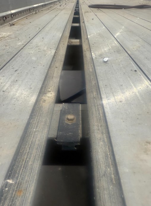 Walking-floor slats with an open channel exposing a T-block and floor supports